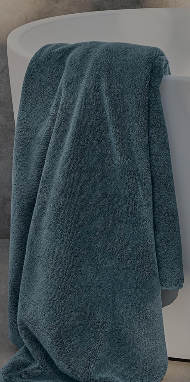 Teal bath towel draped over a white bathtub