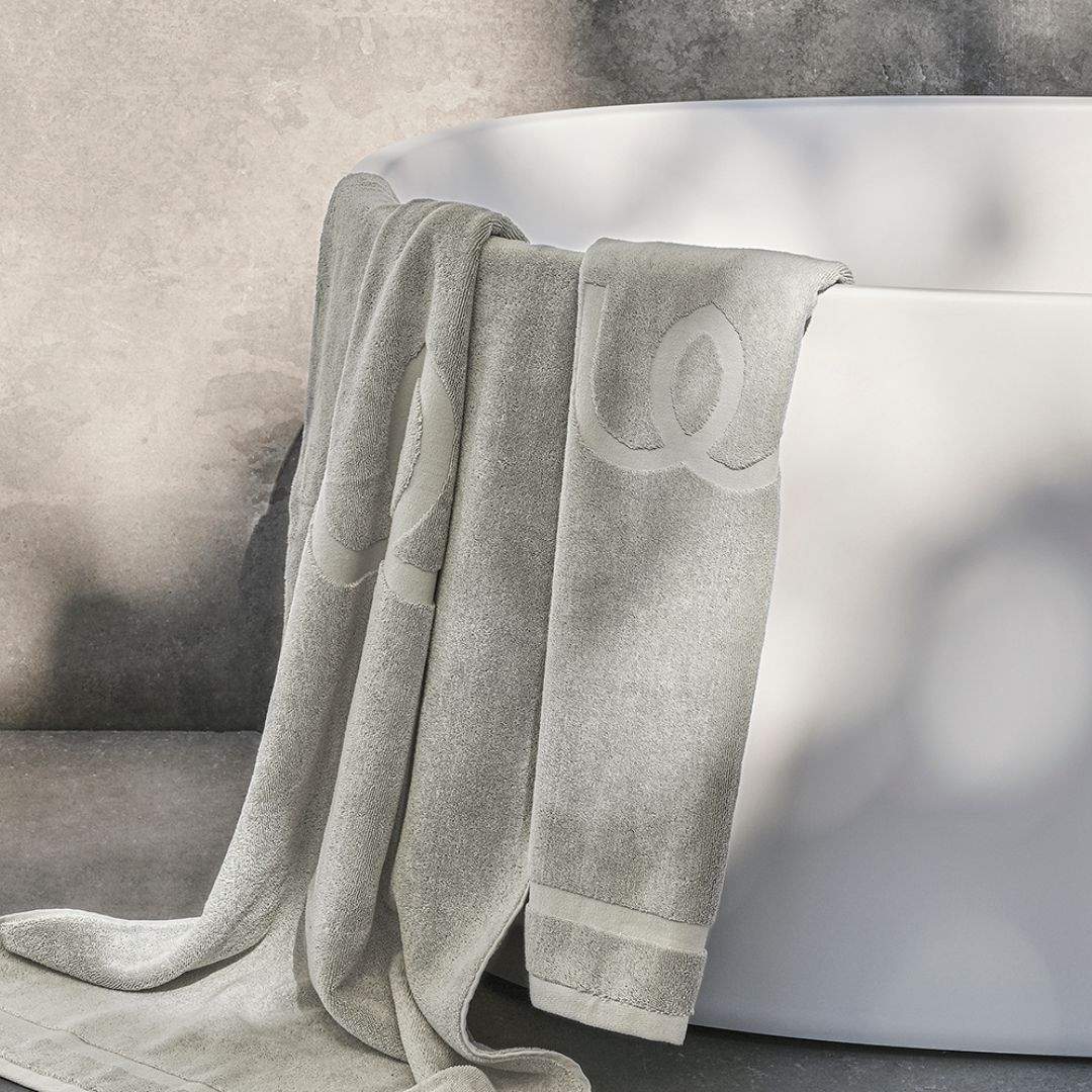 Gray towel draped over a white bathtub with a neutral background.