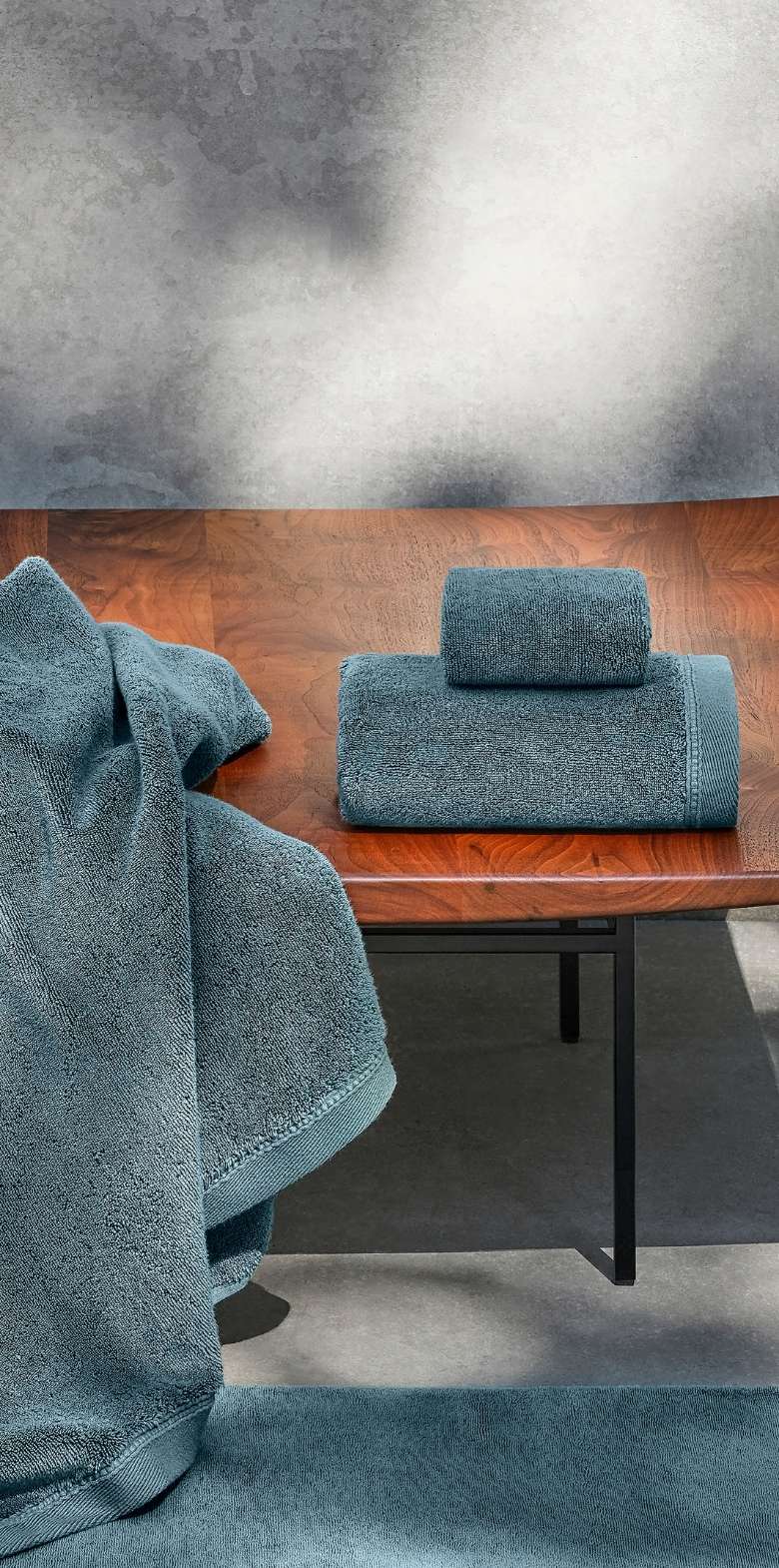 Blue towel on a wooden table with a textured gray wall in the background.